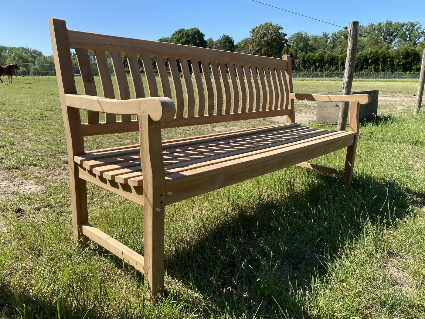 Teakhouten tuinbank van 180 cm met armleuningen, schuin van voren in de zon